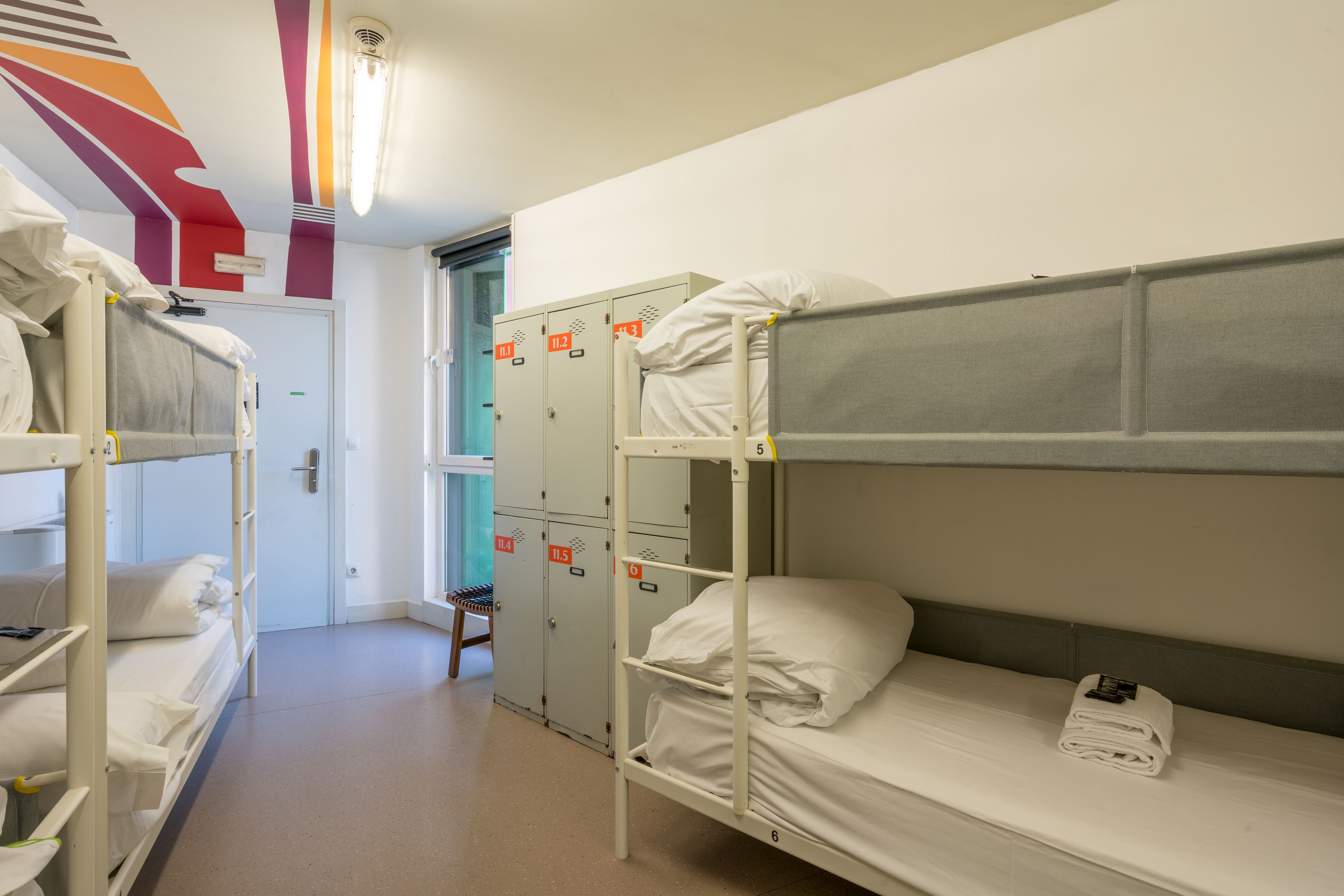 Un dormitorio con literas, una puerta y una fila de taquillas.