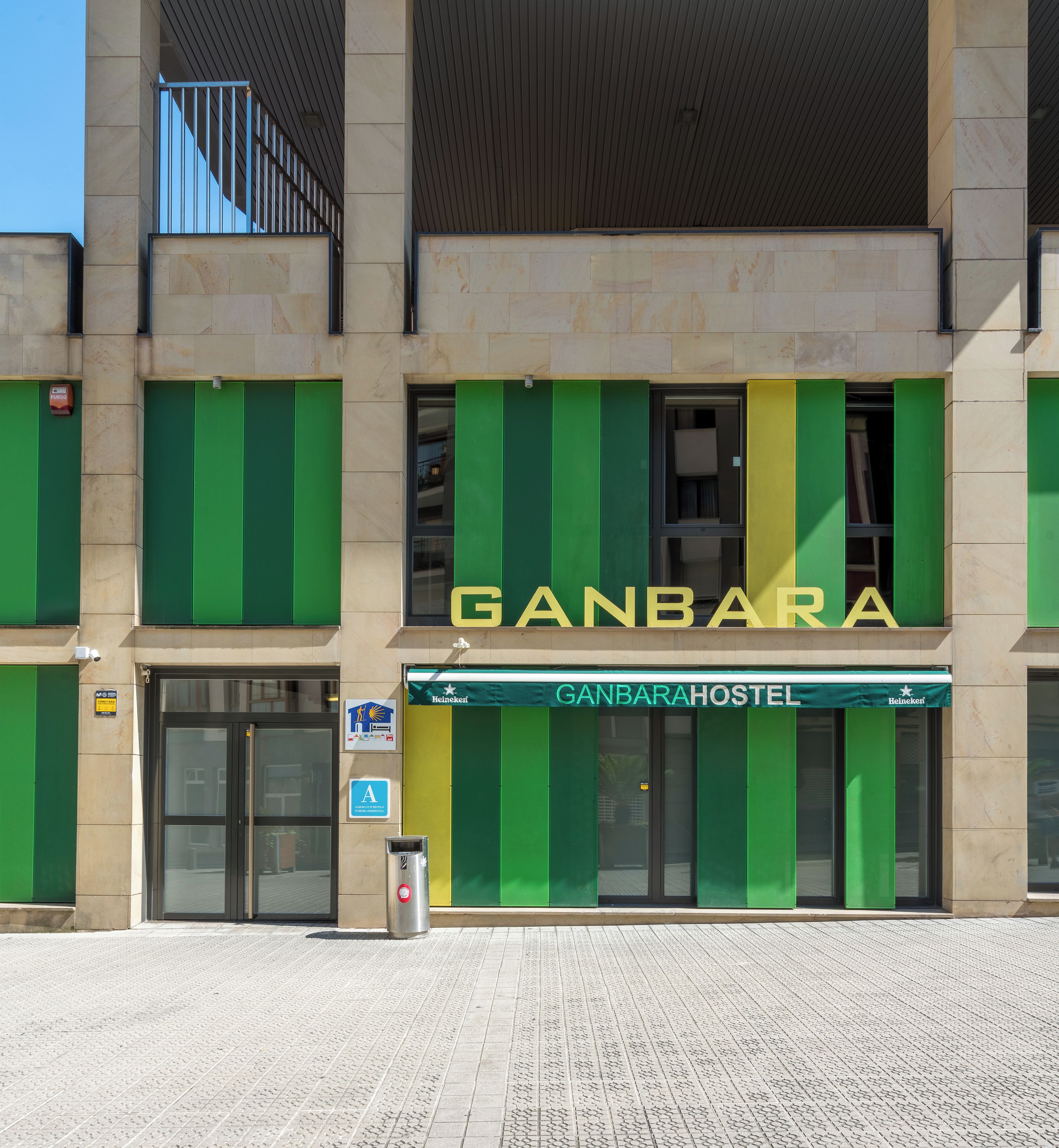 Un edificio con un letrero que dice 'GANBARAHOSTEL' y un cartel de Heineken.