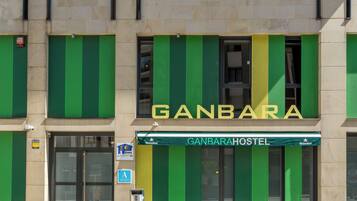Un edificio con un letrero que dice 'GANBARAHOSTEL' y un cartel de Heineken.
