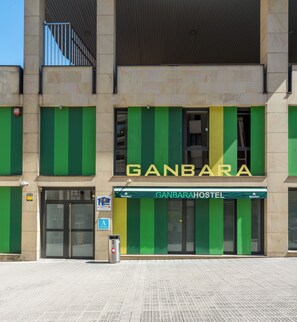 En byggnad med en skylt där det står ”GANBARAHOSTEL” och en Heineken-banner.