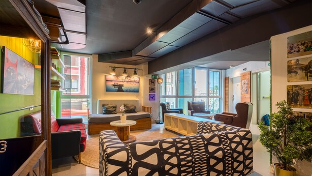 A modern interior with a sofa, a coffee table, and a bookshelf. - Hostal Ganbara (Bilbao)