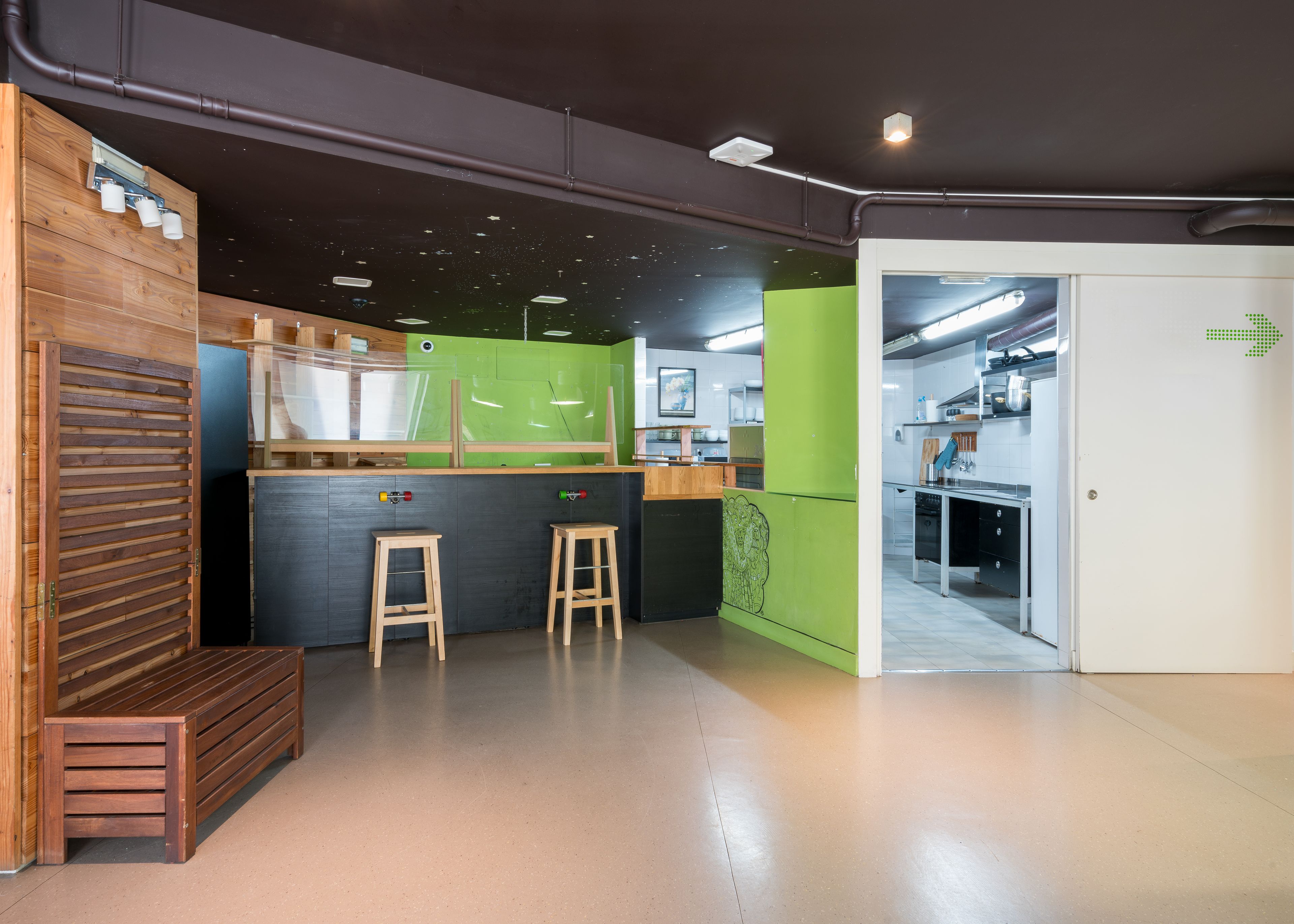 Una cocina moderna con detalles de madera, una pared de acento verde y vistas al área de comedor.