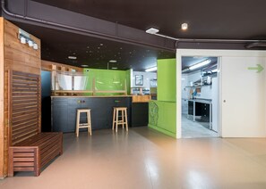 A modern kitchen with wooden accents, a green accent wall, and a view into the dining area. - Hostal Ganbara (Bilbao)