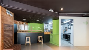 A modern kitchen with wooden accents, a green accent wall, and a view into the dining area. - Hostal Ganbara (Bilbao)