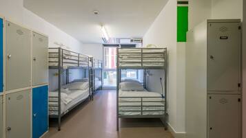 Habitación tipo dormitorio con literas, taquillas y una ventana.