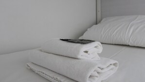 A neatly made bed with white linens and a folded towel on top. - Hostal Ganbara (Bilbao)