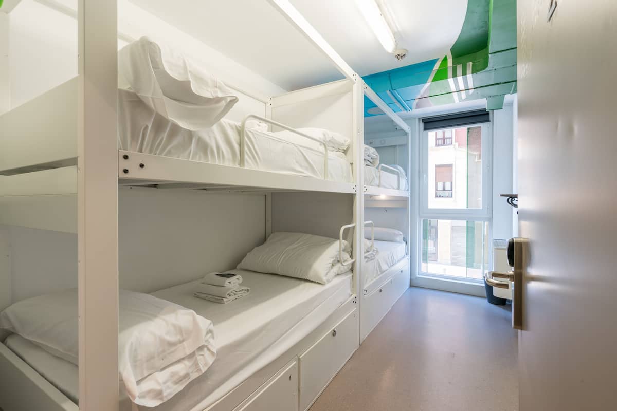 Dormitorio con tres literas, una puerta que da al exterior y una ventana.