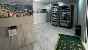 A hotel lobby with a reception desk, a vending machine, and a view of a marina. - Hotel Martini (Casavatore)