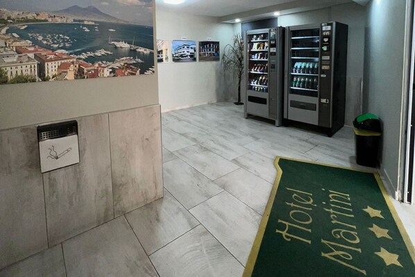 A hotel lobby with a reception desk, a vending machine, and a view of a marina. - Hotel Martini (Casavatore)