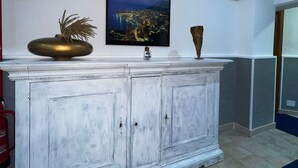 A white cabinet with a television mounted above it, a decorative vase, and a fire extinguisher on the wall. - Hotel Martini (Casavatore)