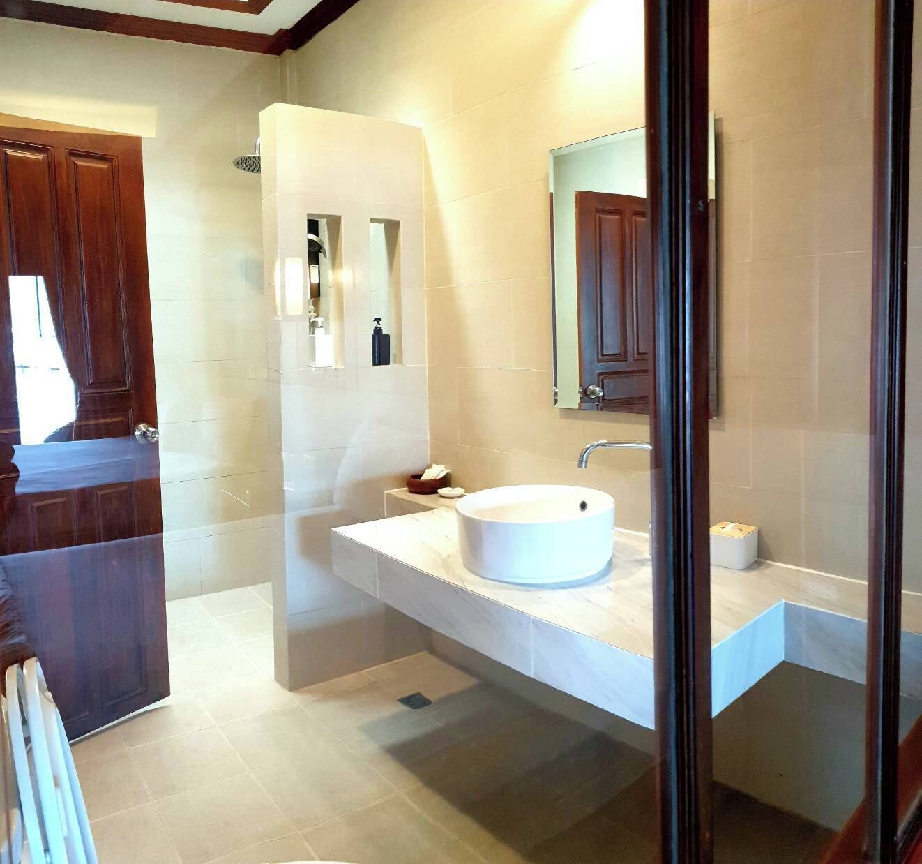 Une salle de bain moderne avec un lavabo blanc, un miroir et un espace douche.