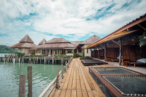 A wooden pier leading to overwater bungalows with thatched roofs, connected by a wooden walkway. - Salakphet Resort (Ko Chang)