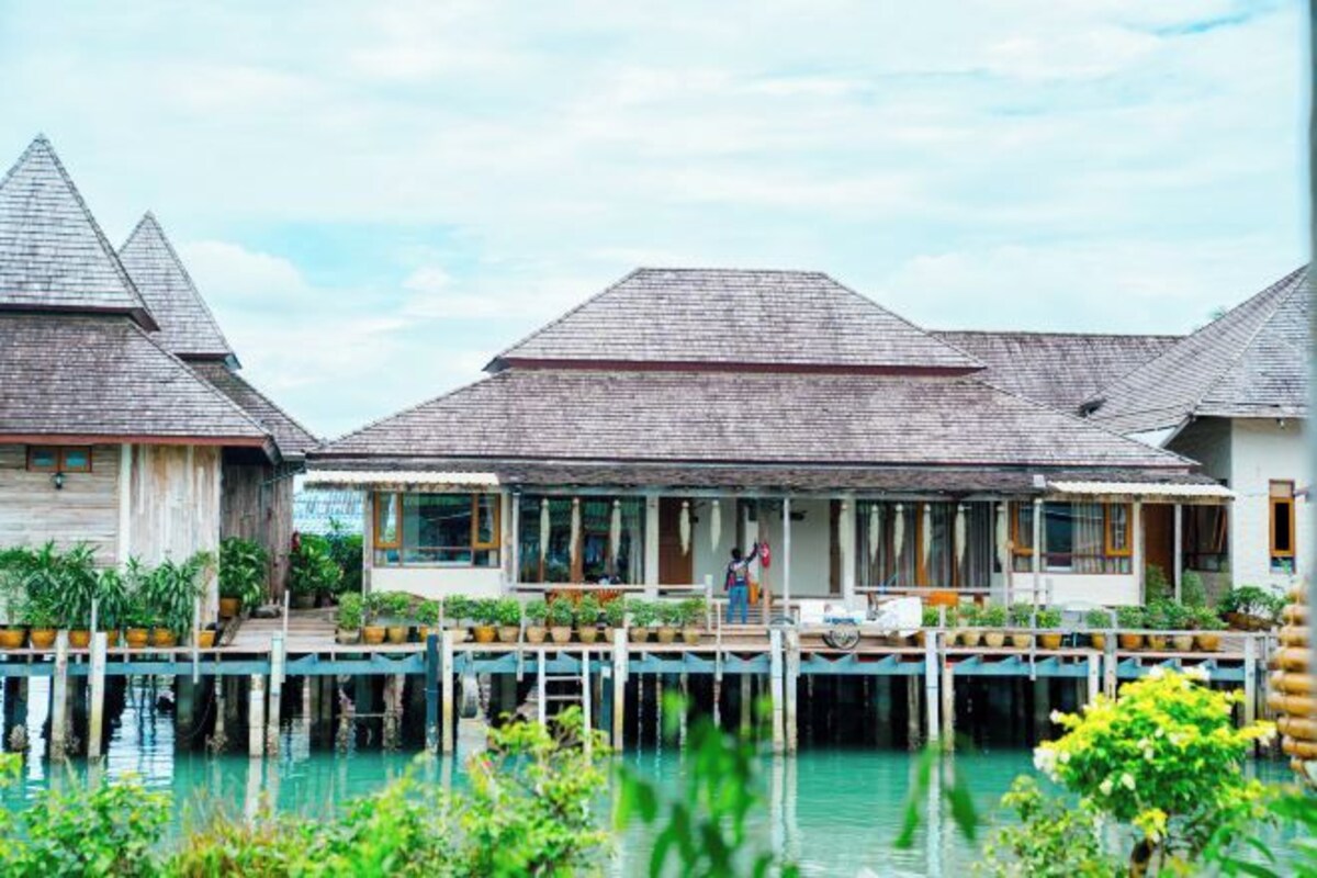 A row of overwater bungalows with a wooden deck and a view of the water.