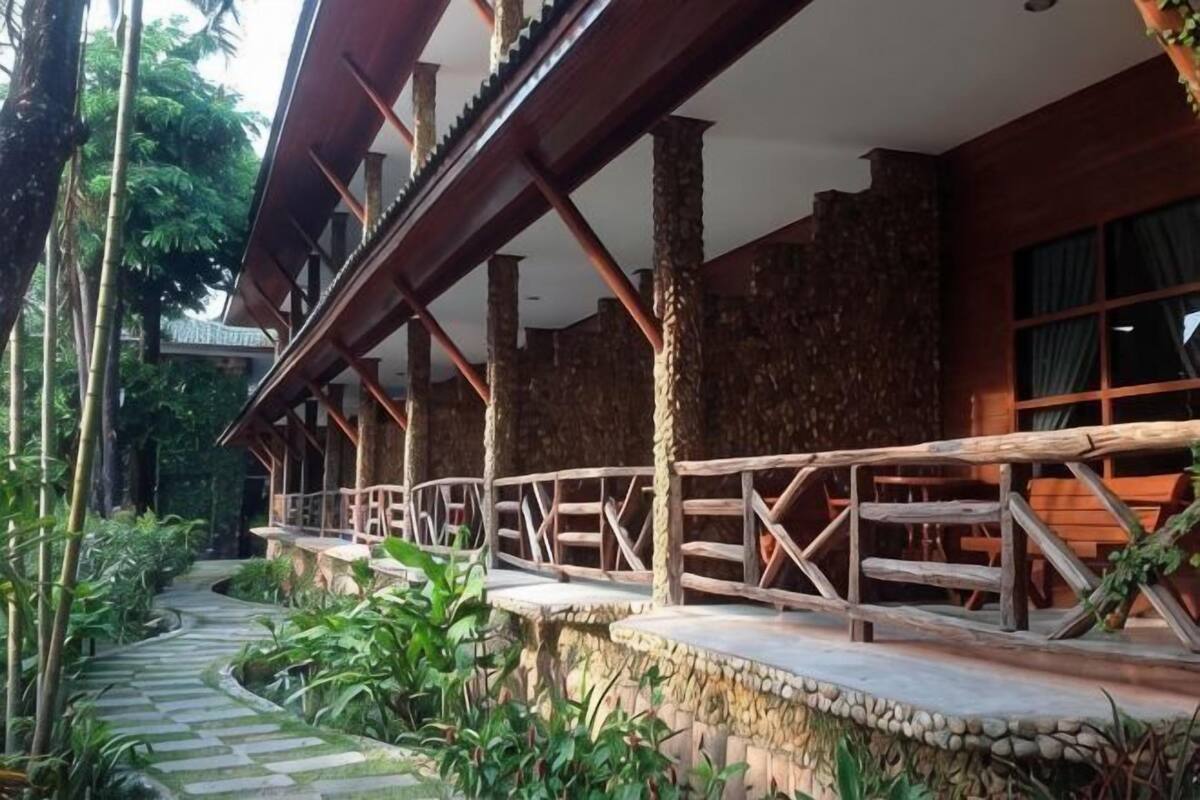 A wooden deck with a stone pathway, surrounded by lush greenery.