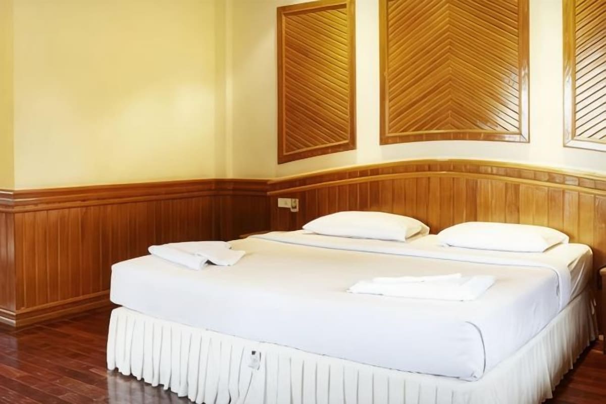 A hotel room with a large bed, wooden paneling on the walls, and a wooden headboard.
