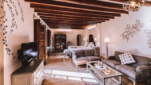 A cozy living room with a wooden ceiling, a television, a sofa, a coffee table, and a lamp.