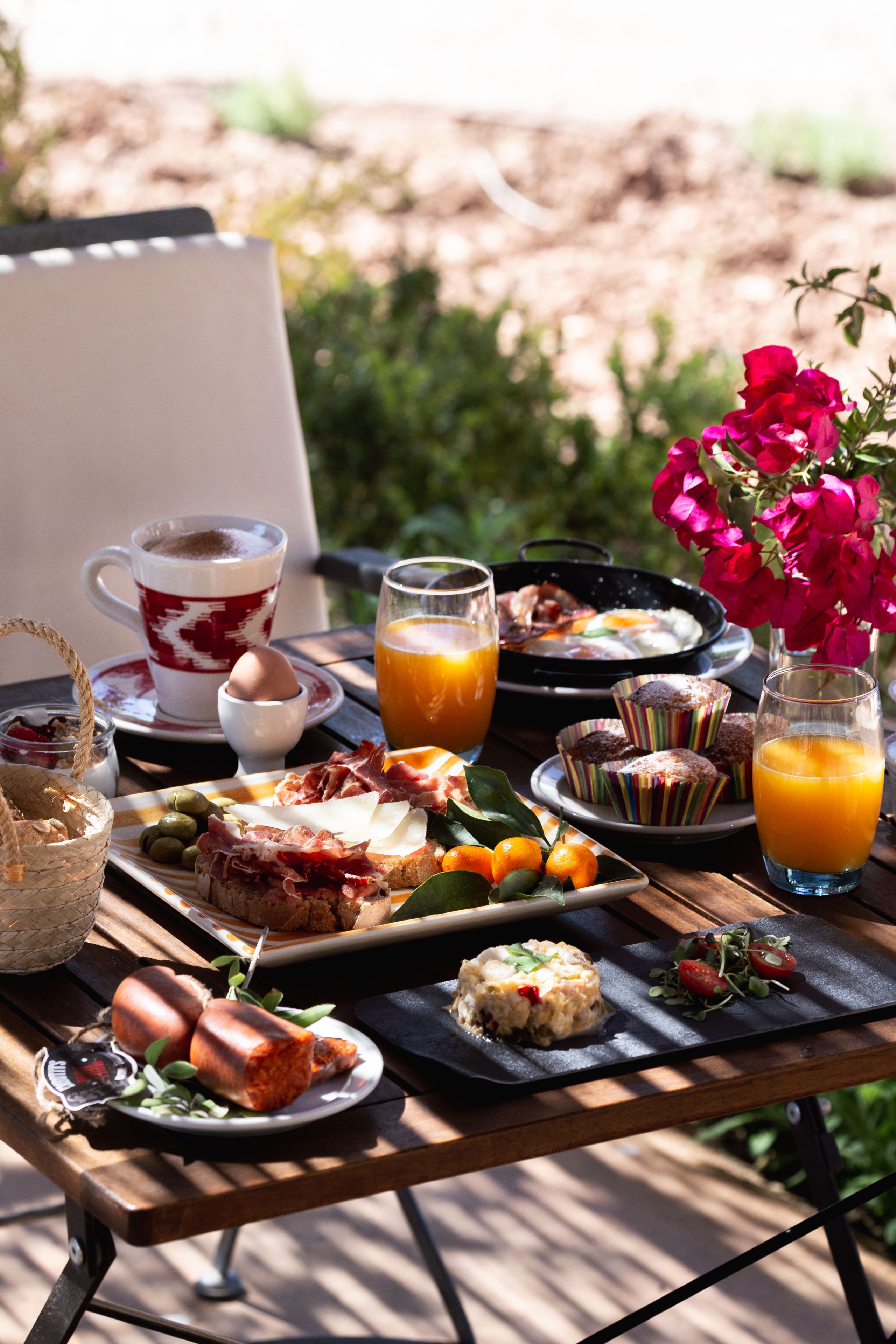 Una mesa de desayuno con diversos alimentos, como pasteles, huevos y jugo.