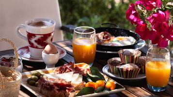 Una mesa de desayuno con diversos alimentos, como pasteles, huevos y jugo.