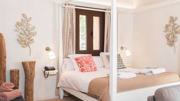 Una cama con dosel con tablero marrón, ropa de cama blanca y una almohada decorativa roja. Hay dos lámparas de pared a cada lado de la cama.