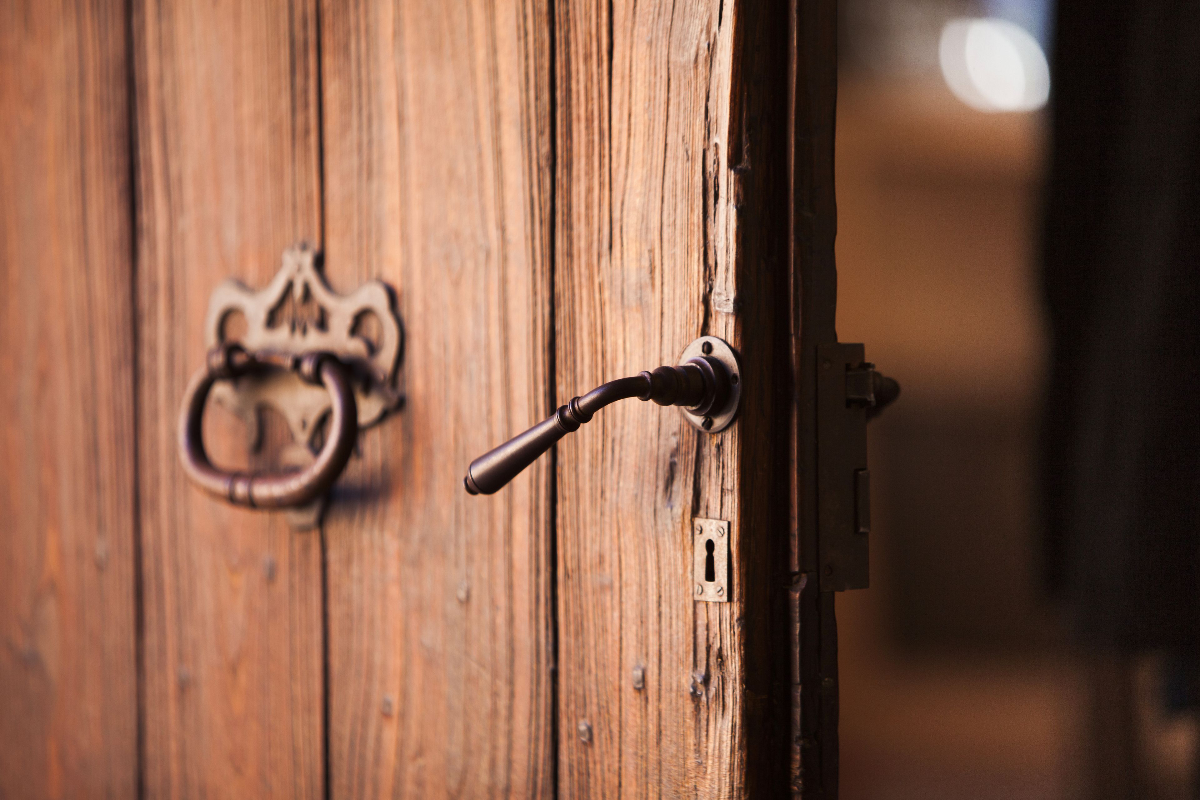 A wooden door with a brass knocker and a keyhole.