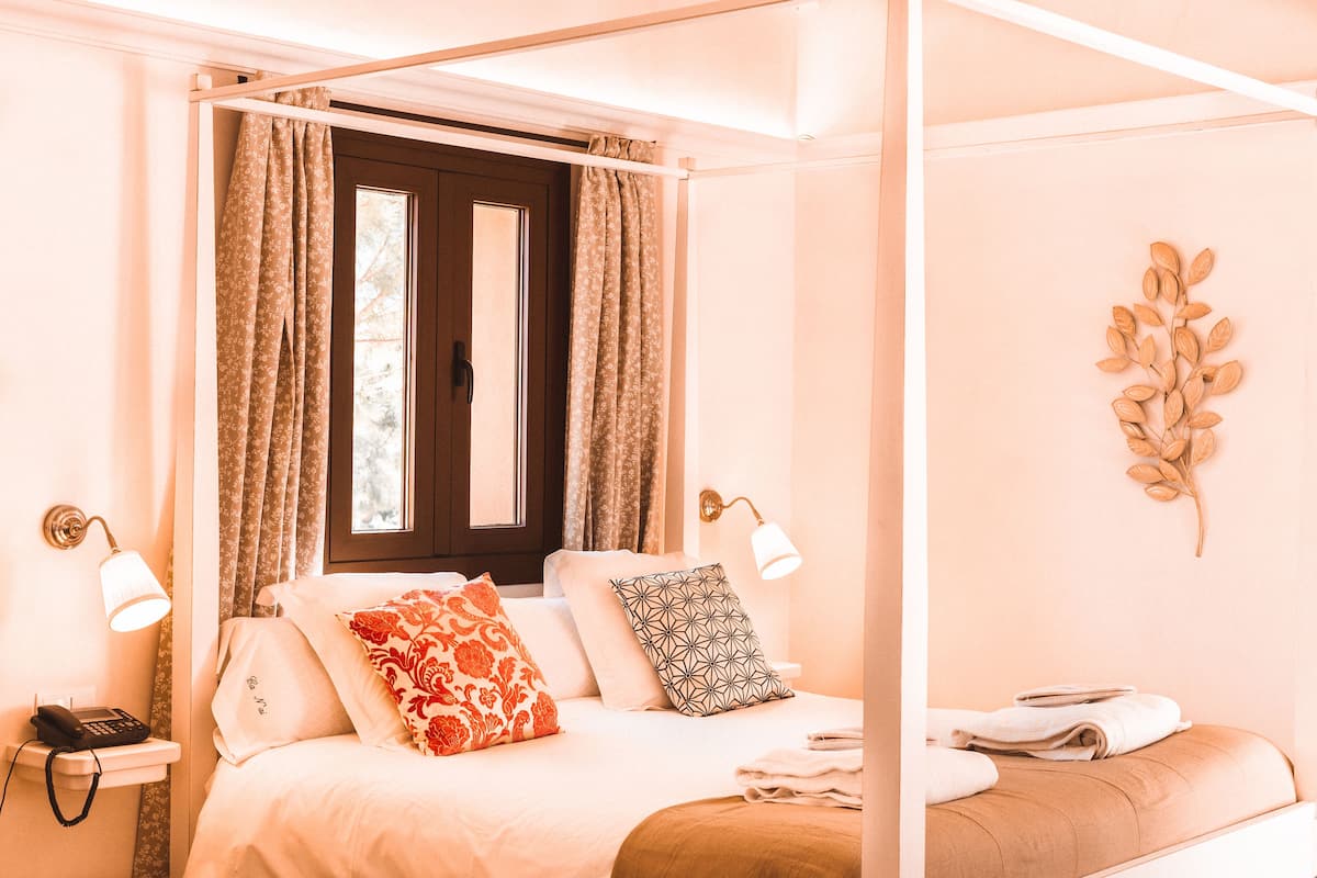 Een hemelbed met baldakijn, een bedtafeltelefoon en een wandlamp.