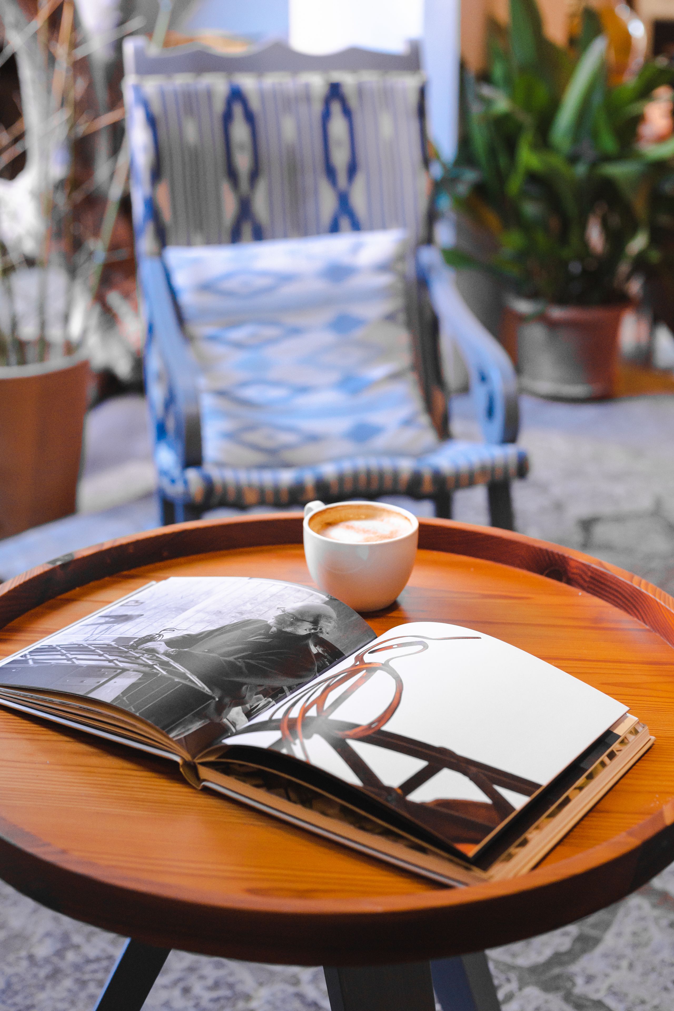Een houten tafel met een tijdschrift, een kop koffie en een stoel op de achtergrond.