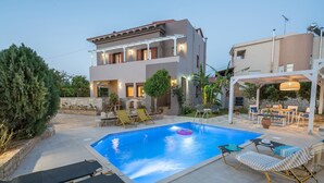 Ein modernes, zweistöckiges Haus mit Swimmingpool, Außenbereich mit Sitzgelegenheiten und einer überdachten Terrasse.