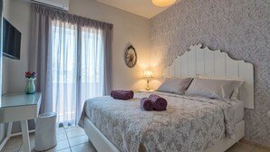 Ein ordentlich eingerichtetes Schlafzimmer mit Bett, Schreibtisch, Lampe und einem an der Wand montierten Fernseher.
