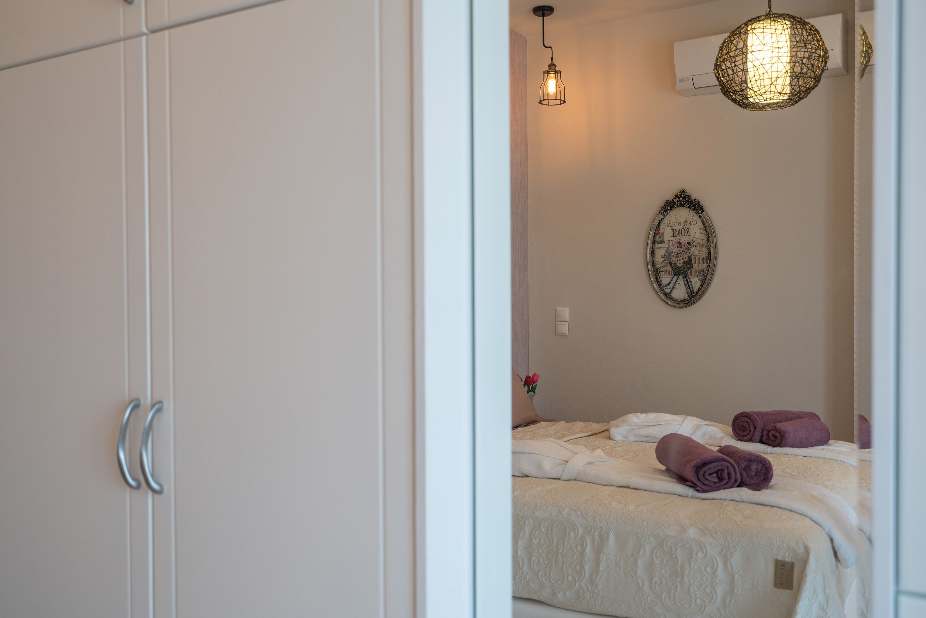 Een slaapkamer met een bed, een hanglamp en een wandairconditioner.