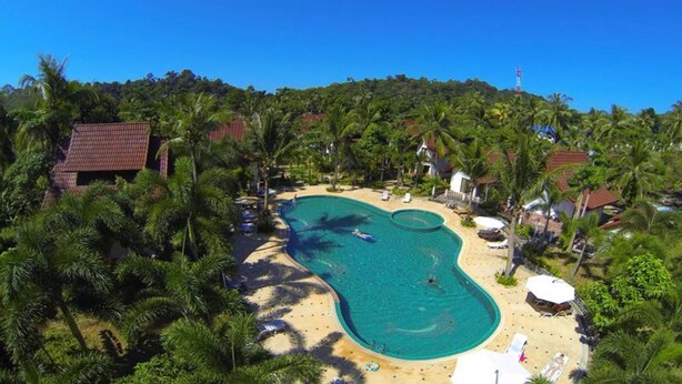 A pool surrounded by palm trees and beach chairs, with a building in the background. - Koh Chang Thai Garden Hill Resort (Ko Chang)