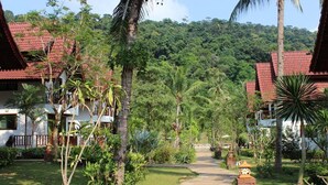 A pathway leading to a building with a red-tiled roof, surrounded by lush greenery and palm trees. - Koh Chang Thai Garden Hill Resort (Ko Chang)