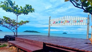 Um deck de madeira com uma placa indicando 'Kai Bae Hut Resort' com vista para um corpo d'água.