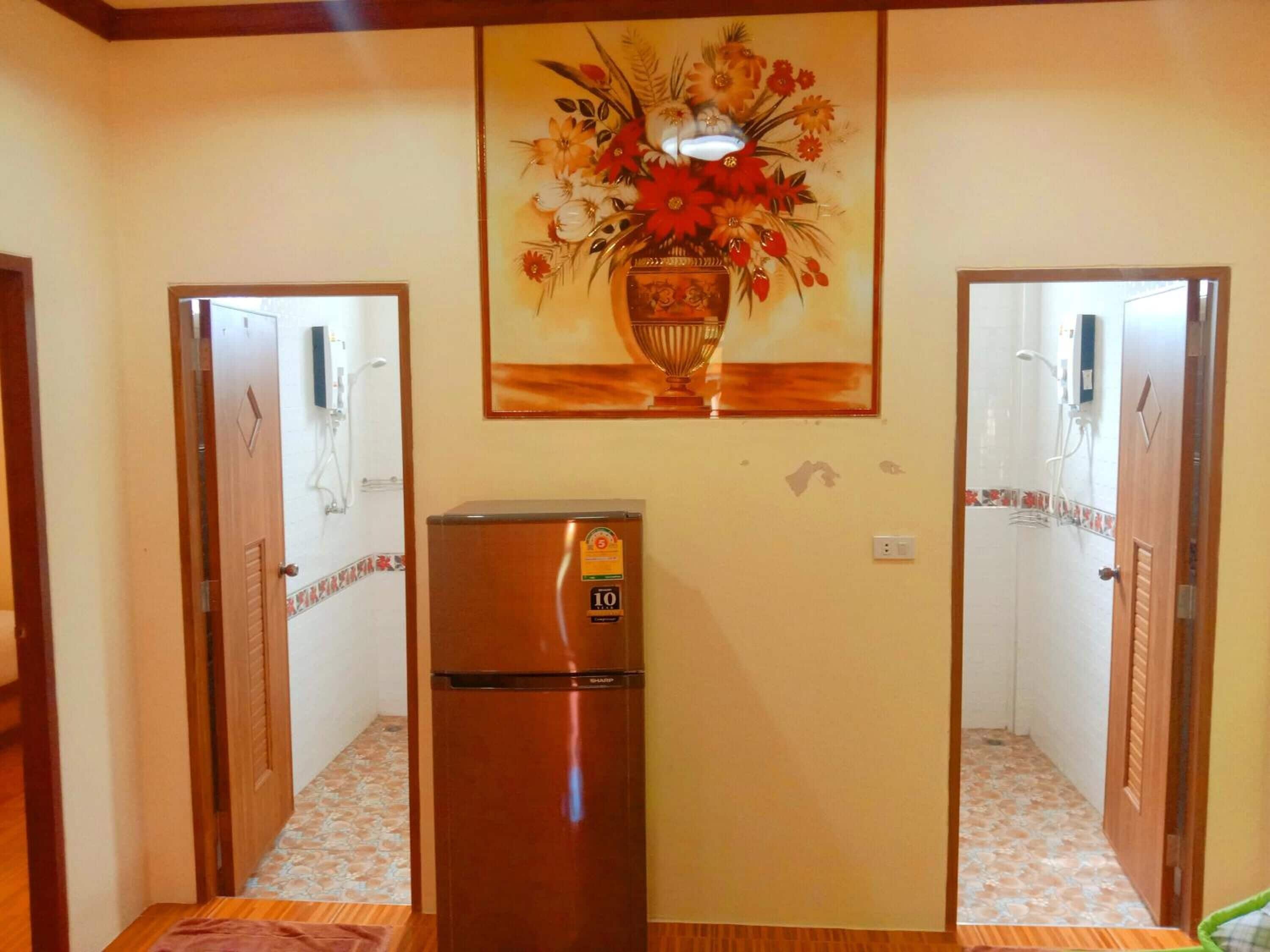 A hallway with a refrigerator, a wall-mounted painting, and two doors.
