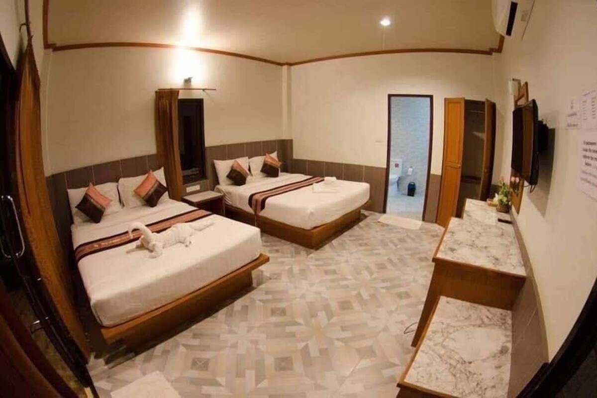 Habitación de hotel con dos camas, baño y una pequeña zona de estar.