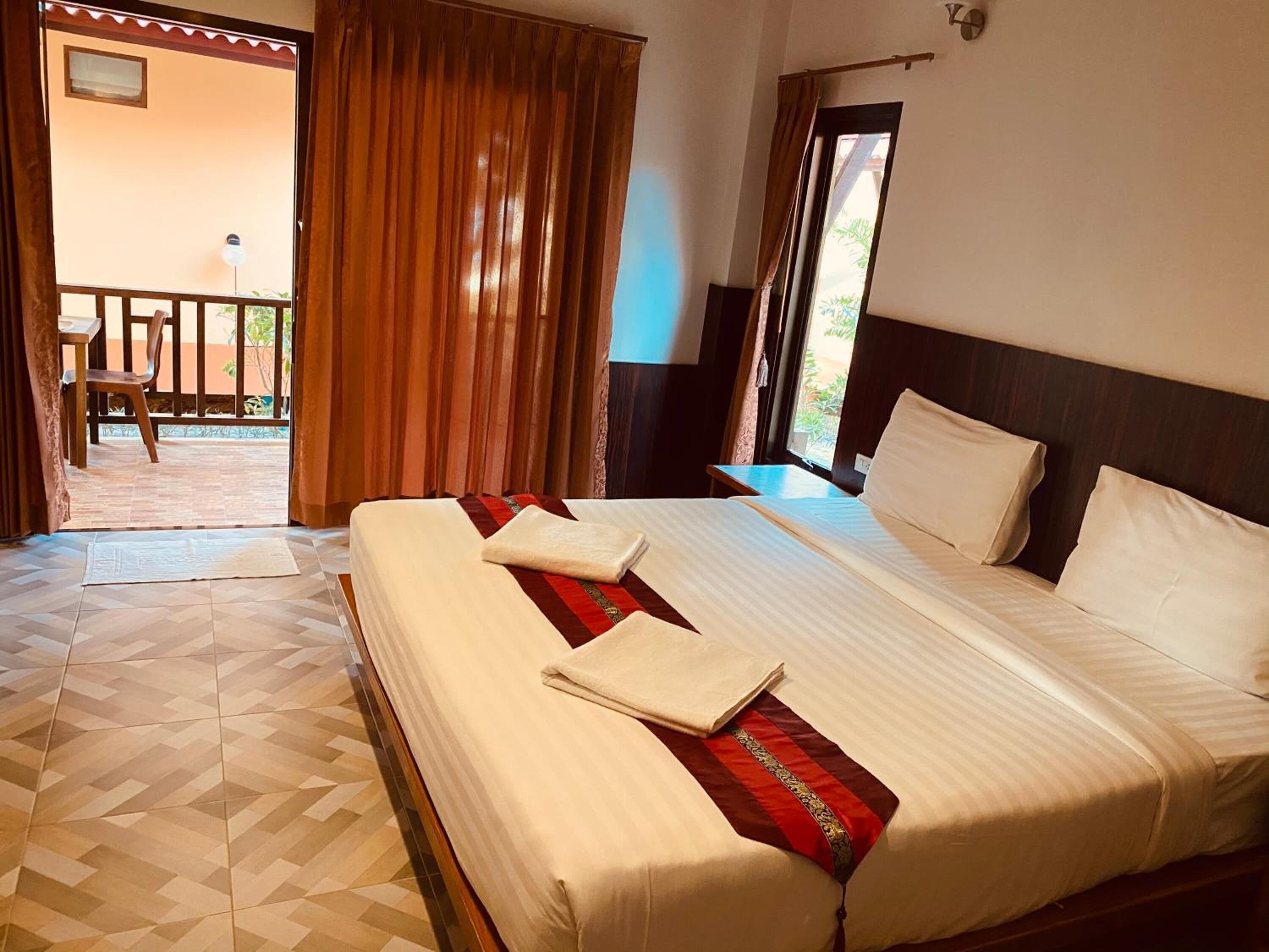 A hotel room with a large bed, a desk, and a view of the outside.