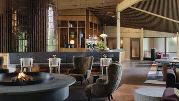 Un vestíbulo moderno con una zona de estar central, un bar y una recepción.