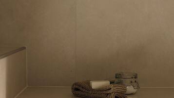 A bathroom with a towel, soap, and a glass jar on a shelf.