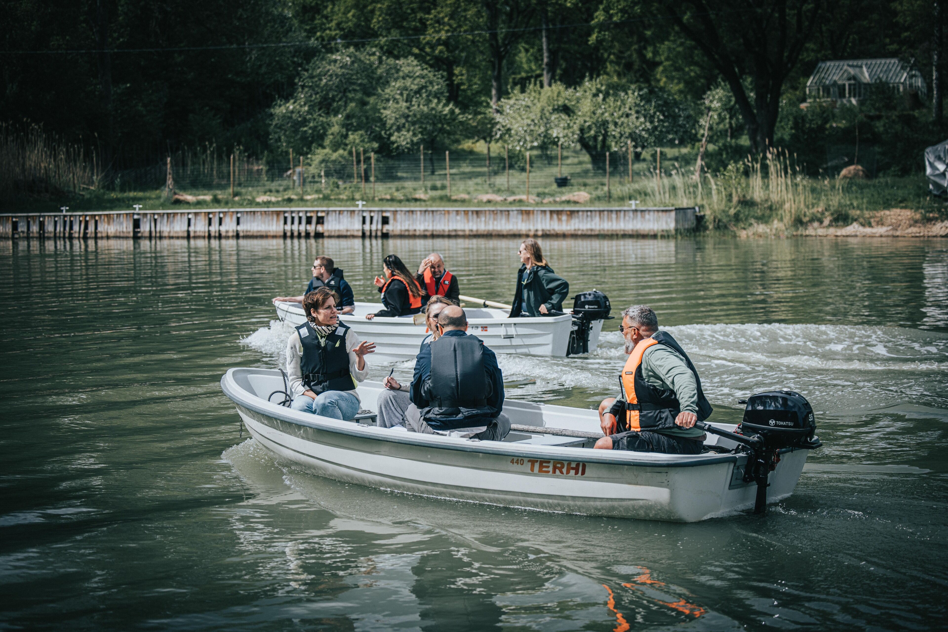 Un petit bateau à moteur avec plusieurs personnes à bord, dont une qui le conduit.