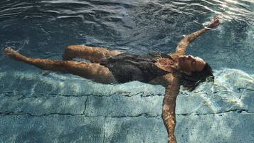 En person som flyter i en pool med klart vatten och en tydlig avgränsning som delar in poolen i banor.