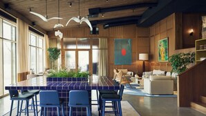 A modern kitchen with a central island, bar stools, and a dining area with a sofa and lamp. - Marholmen Stugor (Norrtälje)