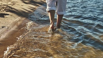 Pés de alguém em águas rasas na praia.