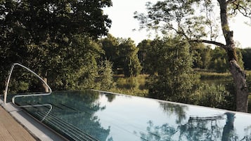 Ein Pool ohne Ende mit freiem Blick auf die umliegenden Bäume und ruhigem Wasser.