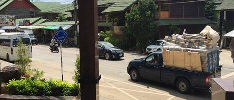 Une vue de rue avec un panneau d’arrêt de bus, une moto garée et un camion chargé de cartons.
