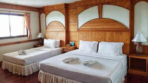A hotel room with two beds, wooden paneling, and a window with curtains.
