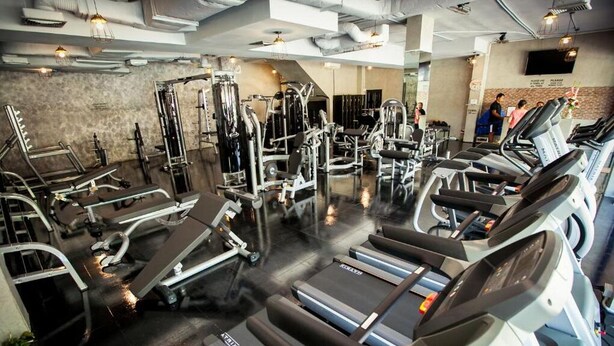 A gym with treadmills, weight machines, and a mirror wall.