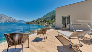 Un balcón con vistas al mar, una piscina y una montaña.