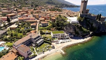 Vista aérea de un pueblo costero con un castillo, una playa y un puerto deportivo.