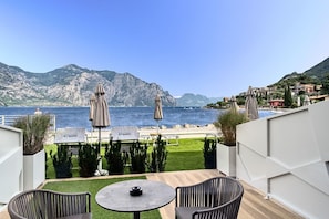 A terrace with a view of the sea, outdoor seating, and a mountain backdrop. - Hotel Castello Lake Front (Malcesine)