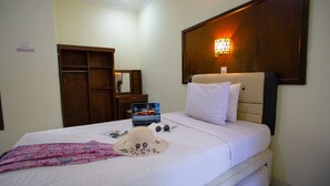 A hotel room with a bed, a laptop, a hat, and a floral blanket. - Teges Inn Kuta (Kuta)