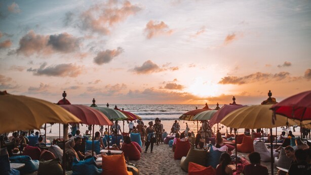 A beach with umbrellas and people relaxing. - Teges Inn Kuta (Kuta)